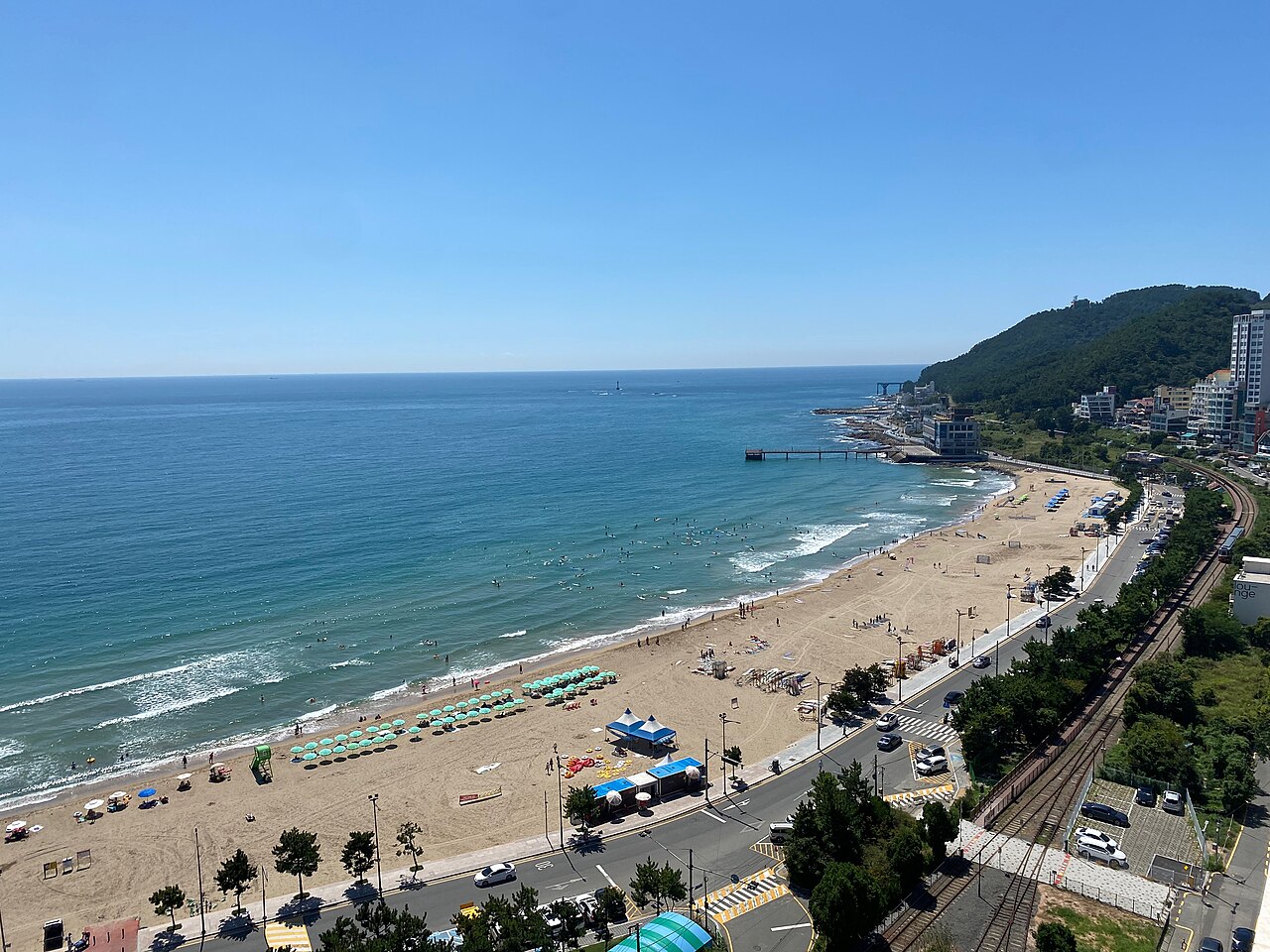 Songjeong Beach with surfboards in the water and the railway beside the shore