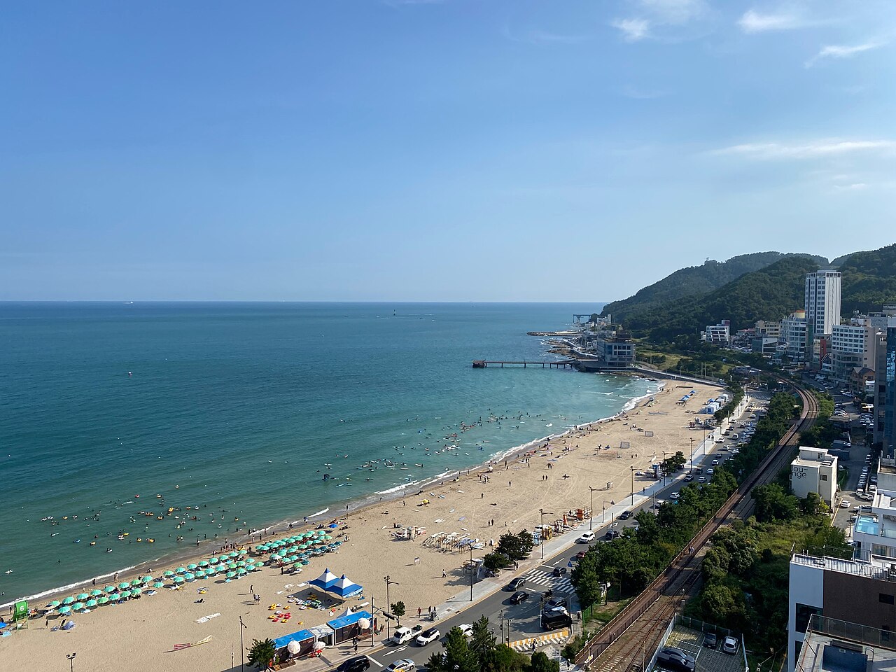 Wide view of people and boards in the sea off Songjeong Beach